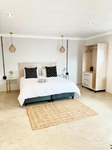 a bedroom with a large white bed and a rug at Lighthouse Guesthouse & Cafe in Groblersdal