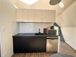 a kitchen with a sink and a microwave in a tent at Glamping Dome - Rosé in Cromwell