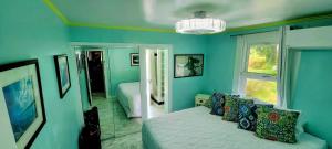 a blue bedroom with a bed and a window at Corner Luxury Ethereal Hawaii Beachfront Estate for Monthly Rental with Private Beach & 3 Beachfront Jacuzzis & Snorkeling Reef & Jurassic Park Film Site in Punaluu