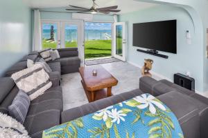 a living room with a couch and a flat screen tv at Corner Luxury Ethereal Hawaii Beachfront Estate for Monthly Rental with Private Beach & 3 Beachfront Jacuzzis & Snorkeling Reef & Jurassic Park Film Site in Punaluu