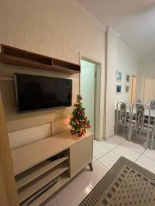 un salon avec une télévision et un arbre de Noël dans l'établissement Apartamento 108 Centro Caragua, à Caraguatatuba