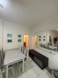 uma sala de jantar com uma mesa, cadeiras e um espelho em Apartamento 108 Centro Caragua em Caraguatatuba