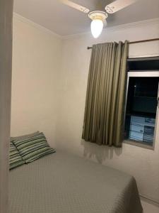 um quarto com uma cama e uma janela com uma cortina em Apartamento 108 Centro Caragua em Caraguatatuba