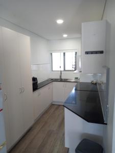 cocina con armarios blancos y encimera negra en Maroochy Sands Holiday Apartments, en Maroochydore