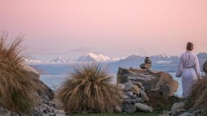 a person sitting on a rock looking at the mountains at Lakestone Lodge in Lake Pukaki