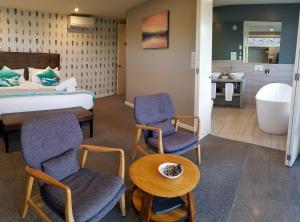 a hotel room with a bed and two chairs and a tub at Lakestone Lodge in Lake Pukaki