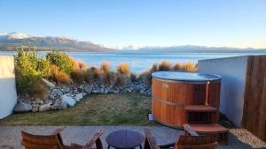 a hot tub sitting on the side of a house with chairs at Lakestone Lodge in Lake Pukaki