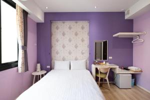 a bedroom with a bed and a purple wall at Wow Haha Foodie House in Anping