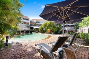 an umbrella and chairs next to a swimming pool at Noosa International Resort in Noosa Heads