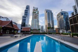 a swimming pool in a city with tall buildings at Ariston Hotel Bangkok in Bangkok