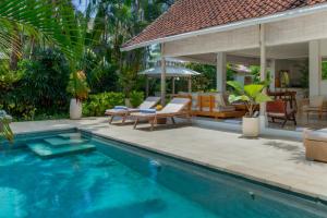 una piscina con sillas y una casa en Villa Rama Sita, en Seminyak