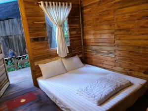 Cama en habitación de madera con ventana en ღ Forest Beach Retreat ღ Sunny Huynh Studio ღ en Phu Quoc