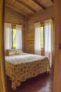 ein Schlafzimmer mit einem Bett in einem Zimmer mit Fenstern in der Unterkunft CASITAS GINGER in Quepos