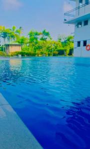 ein großer Pool mit blauem Wasser und Bäumen im Hintergrund in der Unterkunft Hotel Dream Paradise in Ja-Ela