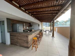 une cuisine avec un bar avec des tabourets et un comptoir dans l'établissement Apartamento Pérola - Zona Sul de Ilhéus - 200 m da praia, à Ilhéus
