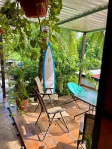two chairs and a surfboard sitting on a patio at Casa Guiba 1 puerto escondido in Puerto Escondido
