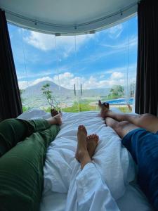 two people laying on a bed in front of a window at Pinggan Cliff in Baturaja