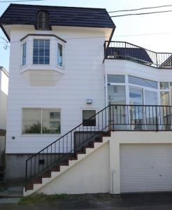 a white house with a staircase in front of it at Snow House Hotel in Sapporo