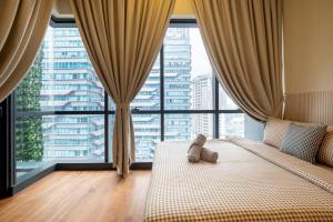 a teddy bear sitting on a bed in a room with large windows at Romantic Couple Bath Tub 6km to KLCC 网红浴缸小红书爆款 in Kuala Lumpur