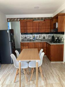 - une cuisine avec une table en bois et des chaises blanches dans l'établissement Apartahotel Villa Carolina 2, à Jericó