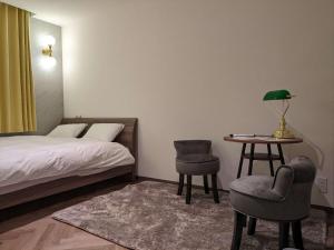 MARUKOU HOTEL في طوكيو: غرفة نوم بسرير وطاولة وكراسي