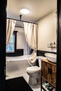 a bathroom with a toilet and a tub and a sink at The Fisherman's Cottage - a Lakeside Loft 