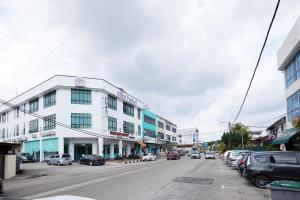 a city street with a white building and parked cars at Elite Hotel in Muar