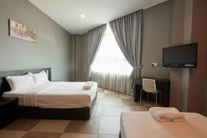 a hotel room with two beds and a flat screen tv at Elite Hotel in Muar