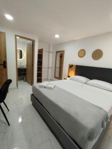 a bedroom with a large white bed and a chair at Zamá Room Hotel in Medellín