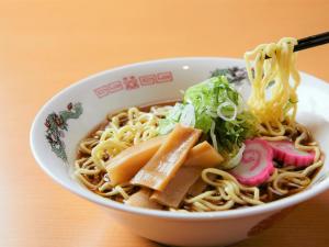 a bowl filled with noodles and vegetables on a table at Hotel WBF Grande Asahikawa in Asahikawa