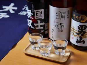 a tray with three glasses and a bottle of wine at Hotel WBF Grande Asahikawa in Asahikawa