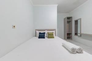 1 dormitorio blanco con 1 cama blanca y 2 almohadas en Urbanview Hotel Sunday Cirebon by RedDoorz, en Cirebon