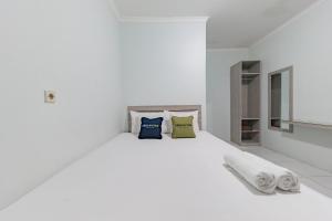 a white bedroom with a white bed with two pillows at Urbanview Hotel Sunday Cirebon by RedDoorz in Cirebon