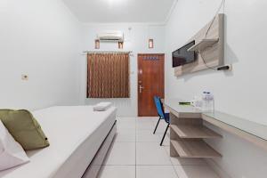 a room with a bed and a desk and a tv at Urbanview Hotel Sunday Cirebon by RedDoorz in Cirebon