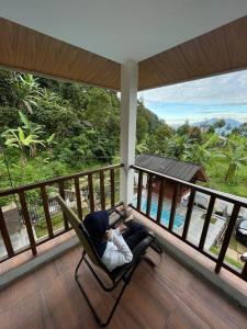 a man sitting in a chair on a porch with a baby at Villa Adendri Riverhills in Megamendung