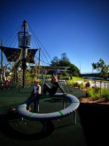 a man and a child sitting on a swing in a playground at Rod 'N' Reel Hotel Motel Woodburn in Woodburn