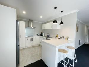 een witte keuken met een aanrecht en 2 krukken bij Modern and Comfortable Home in Flagstaff in Hamilton