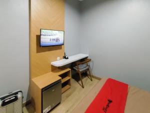 1 dormitorio con escritorio y TV en la pared en RedDoorz Syariah near Tugu Juang Jambi, en Jambi
