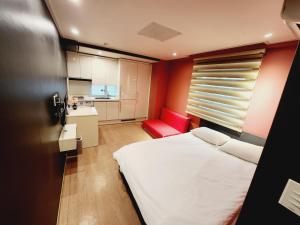 ソウルにあるOlive hostel R(Residence)の小さなベッドルーム(白いベッド1台、赤い椅子付)