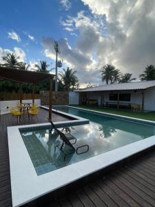 a swimming pool with a deck and a house at Kanto do Chico in Icaraí
