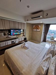 a bedroom with a large bed with a flat screen tv at Warhol Residence at Louis Kienne Semarang Simpang Lima in Semarang