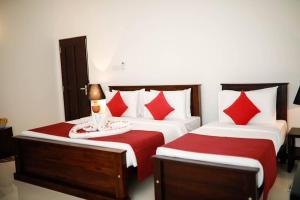 sypialnia z 2 łóżkami i białymi i czerwonymi poduszkami w obiekcie Villa Ayu w mieście Galle