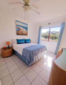 a bedroom with a bed with blue pillows and a window at Ripple in time - 4 Adults & 2 kids Only in Umdloti