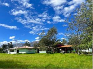 una casa en un campo de hierba con un cielo nublado en Room in Bungalow - Grandfathers Farm - Disfruta de la naturaleza en un lindo flat, en Cajamarca