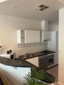 a kitchen with white cabinets and a counter top at RNR Sturt Holiday Home in Adelaide