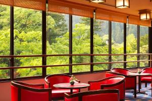 a restaurant with red chairs and tables and large windows at Yamanaka Onsen Kagari Kisshotei in Kaga