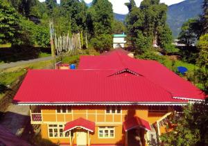 a yellow and red house with a red roof at Karma Homestay by StayApart in Aritar
