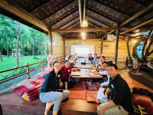 um grupo de pessoas sentadas em torno de uma mesa de madeira em Chomka Thnong Resort 