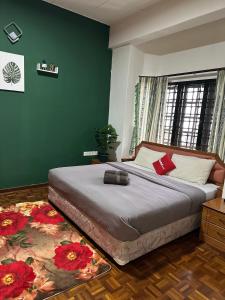 a bedroom with a large bed and a green wall at 100 Oastel coLiving in Tanah Rata