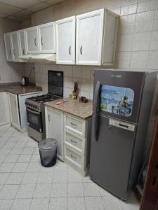  La cuisine est équipée de placards blancs et d'un réfrigérateur. dans l'établissement Ajman preal modren 1 bed room, à Ajman
